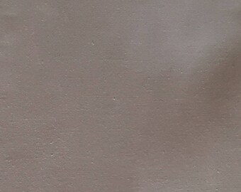 May include: A close-up of a plain, light beige fabric with a subtle texture.