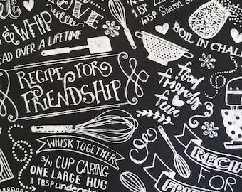 Tela de algodón con estampado de pizarra "Horneado con amor" de Hi-Fashion Fabrics. Frases e imágenes blancas sobre fondo negro. Disponible por medio metro, 45,7 cm x 109 cm.