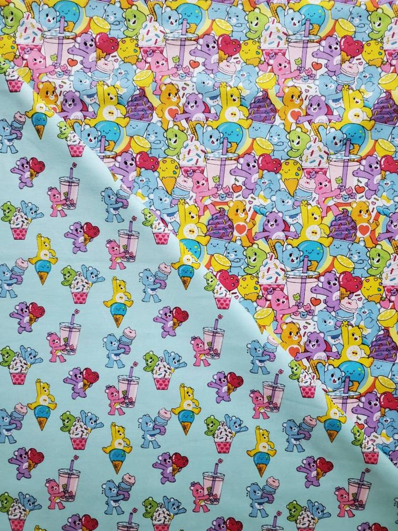 May include: A blue fabric with a repeating pattern of cartoon bears holding ice cream cones, drinks, and cupcakes. The bears are in various colors, including pink, purple, yellow, and blue.