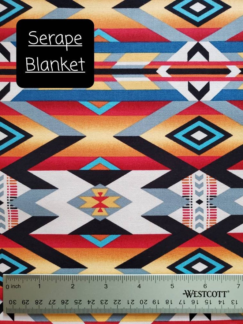 May include: A colorful fabric with a geometric pattern in shades of red, orange, yellow, blue, black, and white. The fabric is labeled "Serape Blanket". A ruler is included for scale.