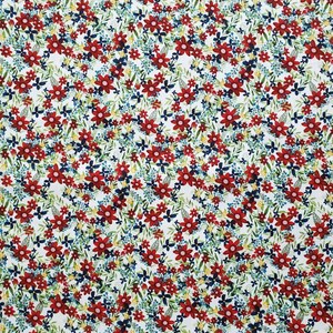 May include: A white fabric with a repeating pattern of red, blue, and yellow flowers. The flowers are small and densely packed, creating a busy floral design.