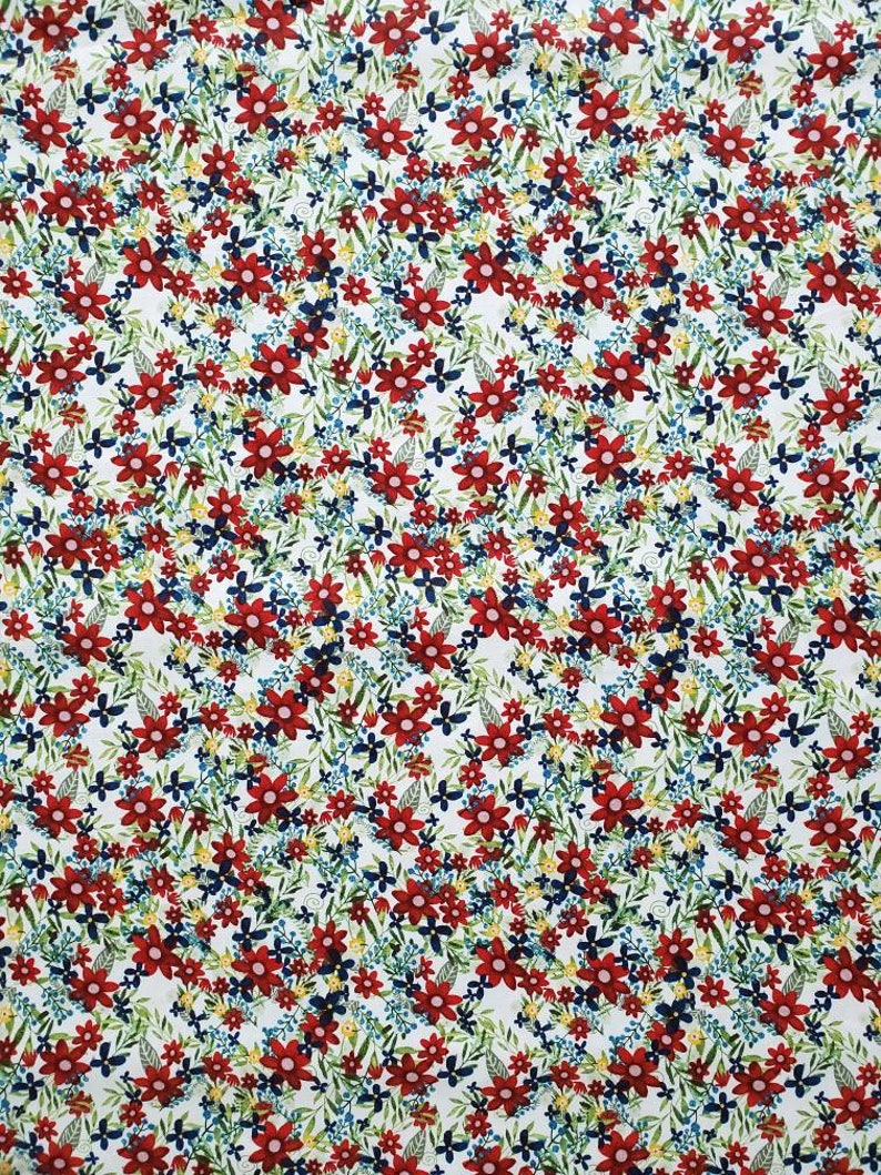 May include: A white fabric with a repeating pattern of red, blue, and yellow flowers. The flowers are small and densely packed, creating a busy floral design.