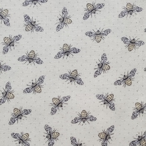 May include: A white fabric with a repeating pattern of black and brown bees. The bees are stylized and have a simple design.