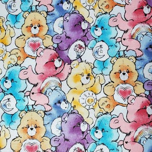 May include: A colorful pattern featuring various Care Bears in shades of blue, pink, yellow, purple, and orange. Each bear has a unique belly badge, including hearts, rainbows, and moons. The bears are set against a white background.