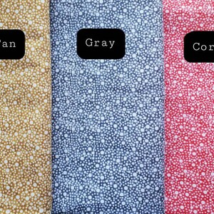 May include: Three fabric swatches with white polka dots on a tan, gray, and coral background. The swatches are labeled "Tan", "Gray", and "Coral".