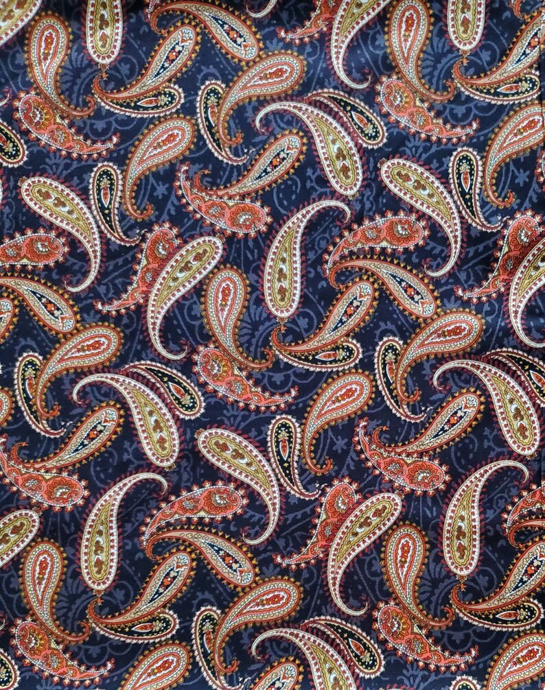 May include: A paisley patterned fabric with a dark blue background. The paisley pattern is in shades of red, orange, yellow, and white.