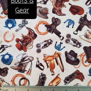 May include: A beige fabric with a repeating pattern of cowboy boots, hats, saddles, and other western gear. The text "Boots & Gear" is printed in black on a black rectangle in the center of the image.