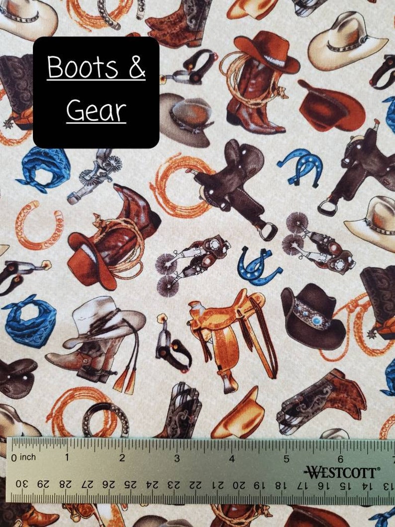 May include: A beige fabric with a repeating pattern of cowboy boots, hats, saddles, and other western gear. The text "Boots & Gear" is printed in black on a black rectangle in the center of the image.