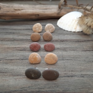 May include: A set of six pairs of earrings made from natural stones. The earrings are in three different colors: brown, red, and beige. The earrings are arranged in three rows of two, with the brown earrings on the bottom row, the red earrings in the middle row, and the beige earrings on the top row.