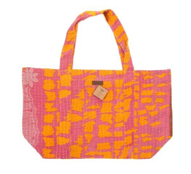 May include: A pink and orange tote bag with a geometric pattern. The bag has two long straps and a small tag with the word "Kantha" on it.