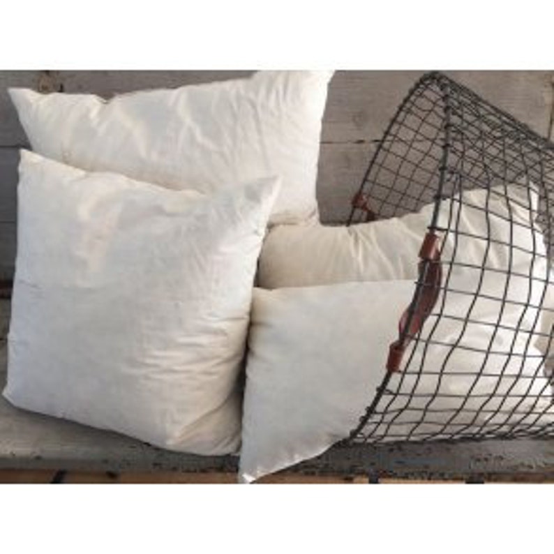 May include: Four white cotton pillow inserts in a wire basket. The pillows are square and have a soft, natural look.