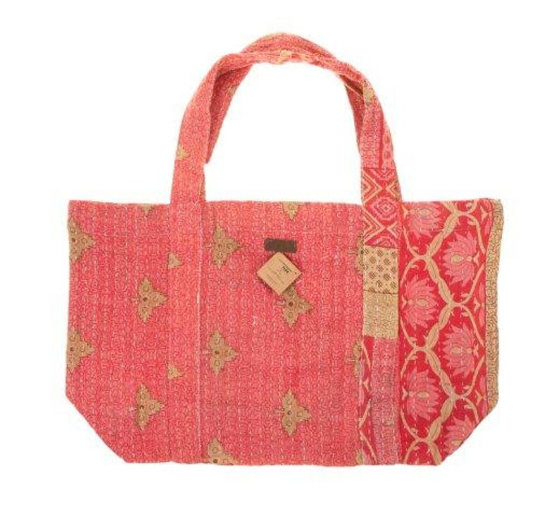 May include: A red and gold patchwork tote bag with a floral pattern. The bag has two handles and a small brown tag attached to the front.