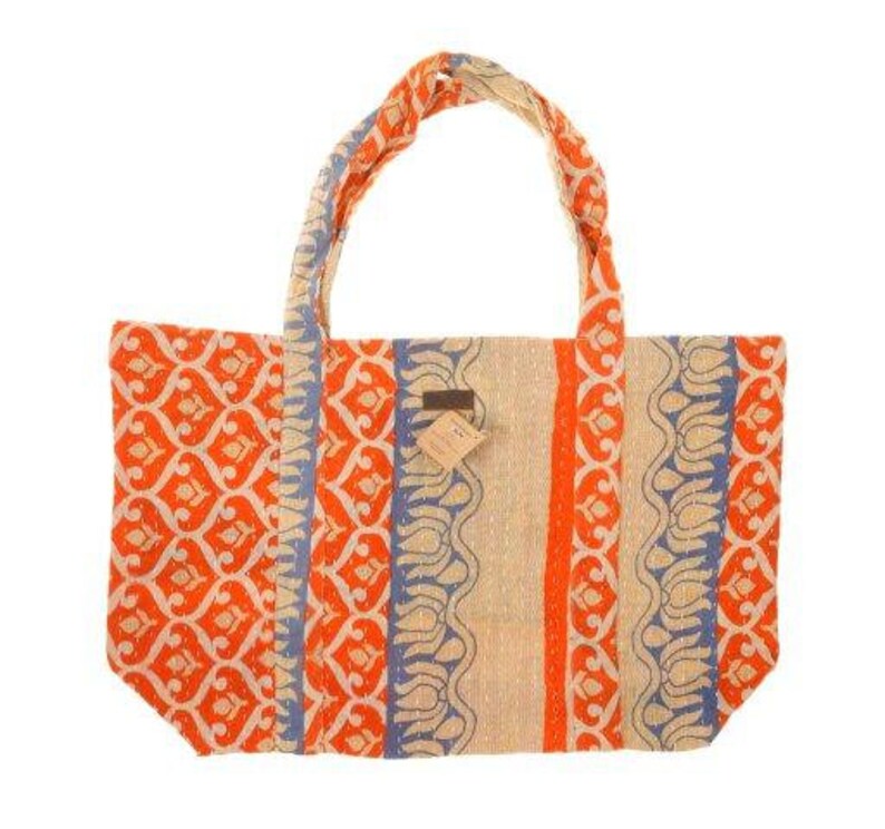 May include: A large tote bag made from recycled fabric. The bag has a beige background with orange and blue patterned stripes. The bag has two long straps.