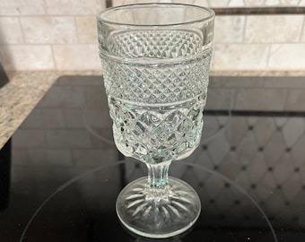 May include: A clear glass goblet with a diamond pattern. The goblet has a stem and a wide base.