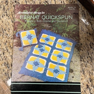 May include: A book titled "Decorative Ideas in Bernat Quickspun" with a blue and yellow crocheted pillow and blanket on the cover. The book is from 1970s and has a price of 75 cents.