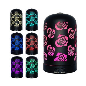 May include: A set of seven black essential oil diffusers with rose patterns. Each diffuser has a different colored light, including yellow, blue, red, purple, and green. The diffusers have a light and mist button.