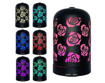 Puede incluir: Un conjunto de siete difusores de aceites esenciales negros con patrones de rosas. Cada difusor tiene una luz de color diferente, incluyendo amarillo, azul, rojo, morado y verde. Los difusores tienen un botón de luz y un botón de niebla.