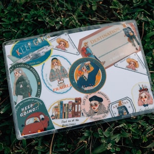 May include: A set of colorful stickers with illustrations of people, airplanes, books, and text that says "Keep Going!" and "Destination: Adventure".