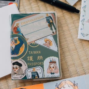 May include: A green passport cover with a variety of colorful stickers. The stickers feature illustrations of people, travel destinations, and the text "TAIWAN 臺灣 身份 PASSPORT".
