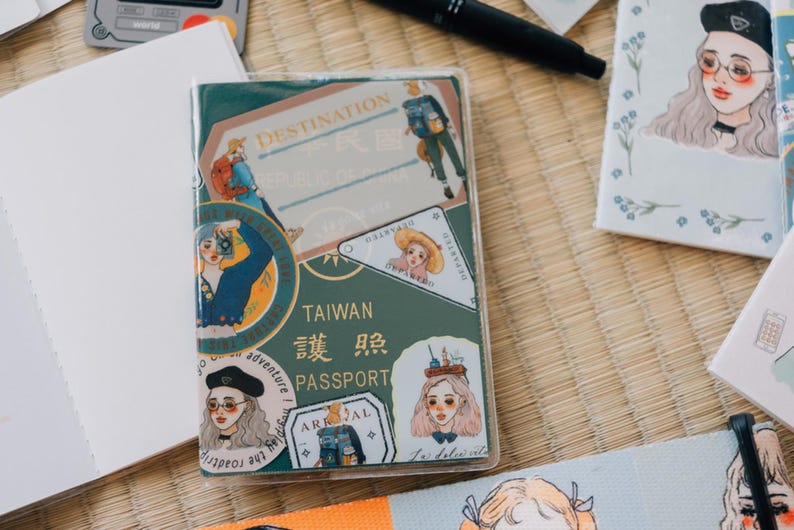 May include: A green passport cover with a variety of colorful stickers. The stickers feature illustrations of people, travel destinations, and the text "TAIWAN 臺灣 身份 PASSPORT".