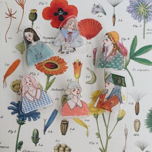 May include: A selection of clear stickers showcasing illustrations of women in diverse attire and hairstyles. The stickers are placed on a background of botanical drawings and floral designs, with a vintage style.