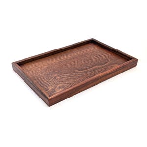 以下が含まれることがあります： 濃い茶色の仕上げが施された長方形の木製トレイ。トレイには縁があり、底は平らです。木目は表面に見えます。トレイは空で、白い背景に置かれています。