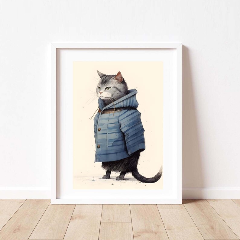 May include: A framed art print featuring a grey tabby cat wearing a blue hooded duffle coat with brown toggle buttons. The cat is depicted in a standing position, facing to the left, against a light cream-coloured background with subtle speckles.