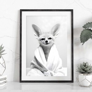 K&ouml;nnte beinhalten: Ein schwarz-wei&szlig; gerahmter Wandkunstdruck, der einen Fennek mit gro&szlig;en Ohren zeigt, der in einen flauschigen wei&szlig;en Bademantel geh&uuml;llt ist. Der Fuchs hat einen sanften Ausdruck und ist in einem d&uuml;nnen schwarzen Rahmen zentriert, was ein kontrastreiches Portr&auml;t ergibt.