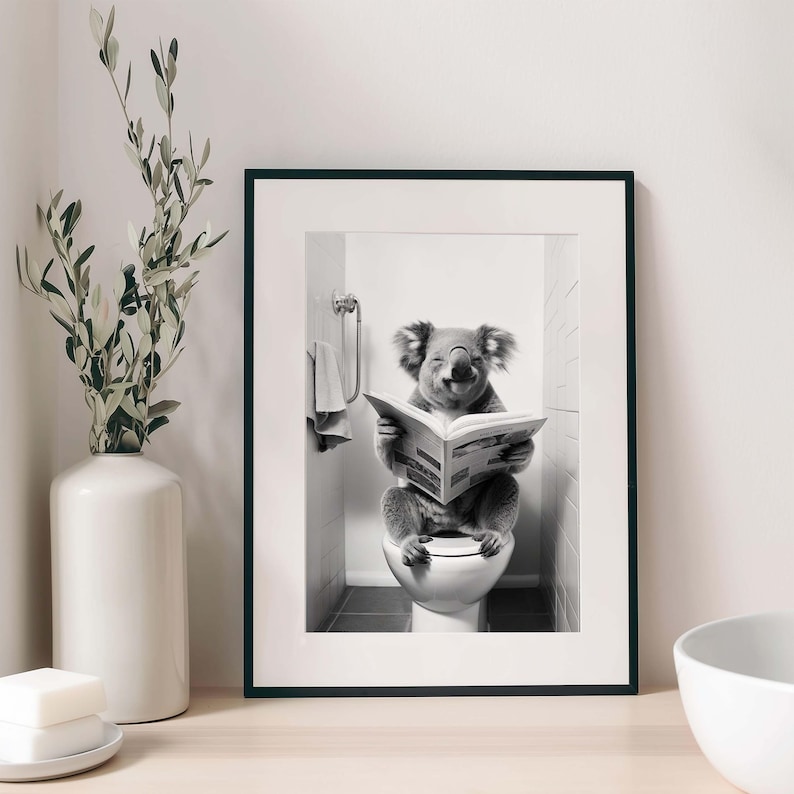 Puede incluir: Una l&aacute;mina de arte mural en blanco y negro enmarcada que muestra a un koala sentado en un inodoro leyendo un peri&oacute;dico. El koala est&aacute; situado en un ba&ntilde;o con azulejos. La l&aacute;mina est&aacute; dentro de un marco negro sencillo con un paspart&uacute; blanco.