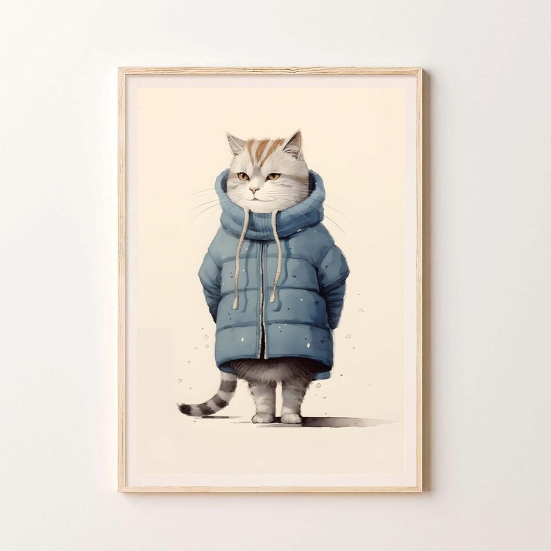 May include: A framed wall art print featuring a light-colored tabby cat wearing a blue puffer jacket with a high collar and drawstrings. The cat has grey and white fur with orange markings on its head and a striped tail, standing upright.