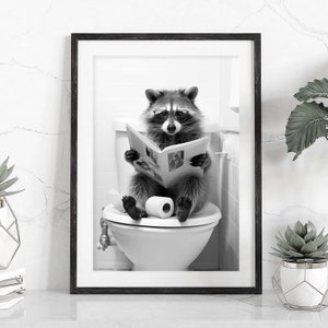 May include: A black and white framed wall art print featuring a raccoon wearing glasses, sitting on a white toilet, and reading an open newspaper. A roll of toilet paper sits on the seat between the raccoon's feet in this humorous bathroom scene.