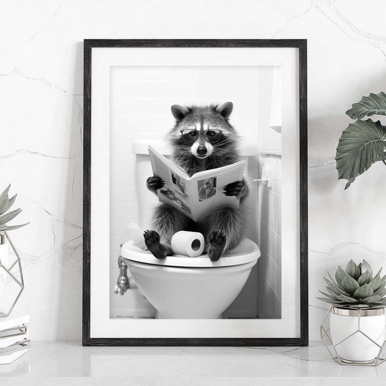 May include: A black and white framed wall art print featuring a raccoon wearing glasses, sitting on a white toilet, and reading an open newspaper. A roll of toilet paper sits on the seat between the raccoon's feet in this humorous bathroom scene.