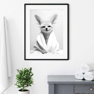 K&ouml;nnte beinhalten: Ein schwarz-wei&szlig; gerahmter Wandkunstdruck, der einen W&uuml;stenfuchs mit gro&szlig;en Ohren zeigt, welcher in ein wei&szlig;es Handtuch eingewickelt ist. Der Fuchs hat ein dezentes L&auml;cheln und ist mittig im Rahmen platziert, der einen d&uuml;nnen schwarzen Rand hat.