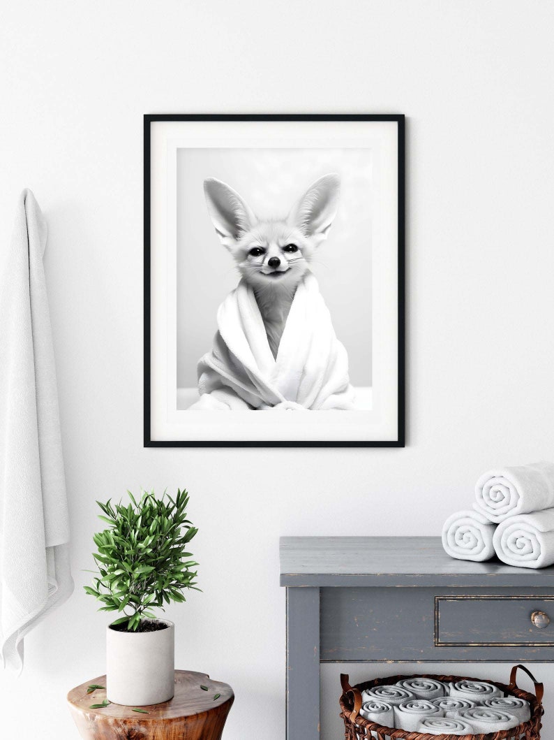 K&ouml;nnte beinhalten: Ein schwarz-wei&szlig; gerahmter Wandkunstdruck, der einen W&uuml;stenfuchs mit gro&szlig;en Ohren zeigt, welcher in ein wei&szlig;es Handtuch eingewickelt ist. Der Fuchs hat ein dezentes L&auml;cheln und ist mittig im Rahmen platziert, der einen d&uuml;nnen schwarzen Rand hat.