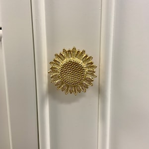 May include: A gold sunflower-shaped cabinet knob with a textured centre.