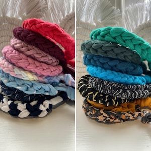 May include: A stack of colourful crocheted headbands in various colours, including red, pink, blue, green, and black. The headbands are made from a soft, stretchy fabric and are perfect for adding a pop of colour to any outfit.