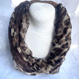 May include: A brown and tan leopard print scarf with brown lace trim.