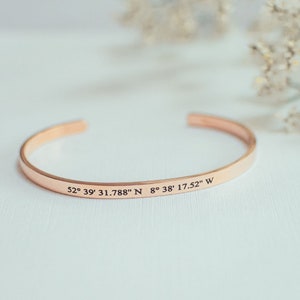 Puede incluir: Un brazalete de oro rosa con las coordenadas "52&deg; 39' 31.788" N 8&deg; 38' 17.52" W" grabadas.