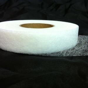 May include: A roll of white fusible web, a type of adhesive fabric used for crafts and sewing projects.