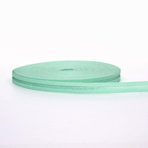 Puede incluir: Un rollo de cinta de tela verde claro con una superficie ligeramente texturizada.