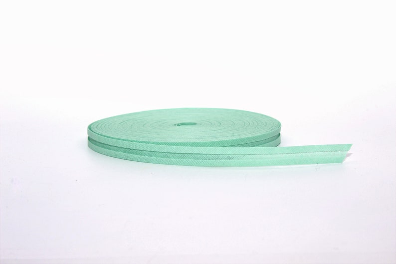 Puede incluir: Un rollo de cinta de tela verde claro con una superficie ligeramente texturizada.