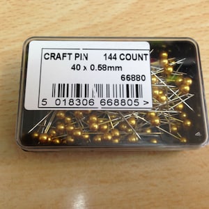 May include: A clear plastic container filled with 144 gold craft pins. The pins are 40 x 0.58mm and have a gold head. The container has a label that reads "CRAFT PIN 144 COUNT 40 x 0.58mm 66880 5 018306 668805 >".