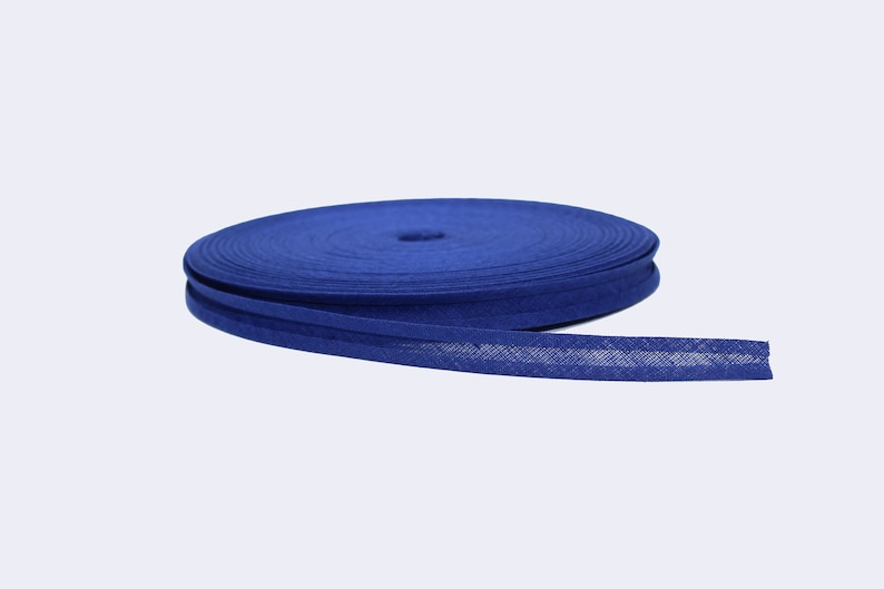 Puede incluir: Un rollo de cinta de bies azul, un tipo de adorno de tela que se utiliza para terminar los bordes de la tela.