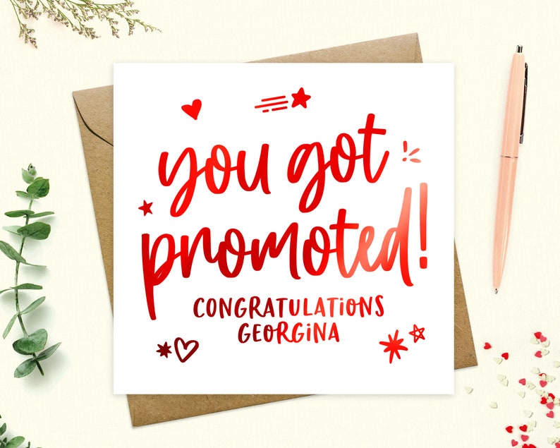 May include: A white card with red foil lettering that says "You got promoted! Congratulations Georgina". The card is decorated with red hearts and stars.