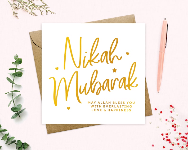May include: A white card with gold lettering that says "Nikah Mubarak" and "May Allah bless you with everlasting love & happiness".