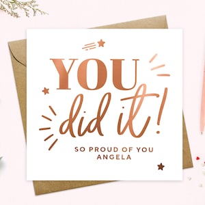 May include: A white card with a copper foil design that says "YOU did it!" and "SO PROUD OF YOU ANGELA".
