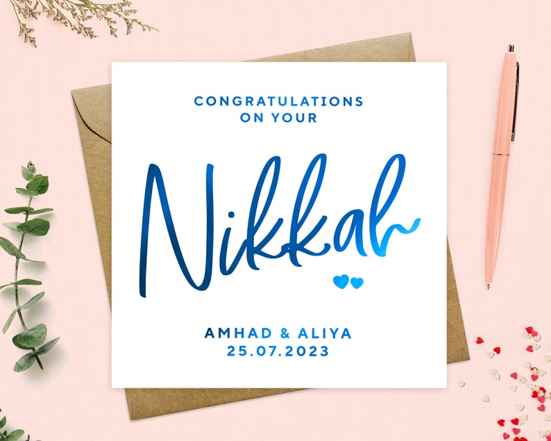 May include: A white card with blue text that says "Congratulations on your Nikkah" with two small blue hearts below the text. The card also says "Ahmad & Aliya 25.07.2023".