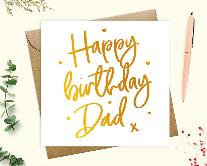 May include: A white card with gold foil lettering that says "Happy birthday Dad" with a small gold cross at the end of the text.