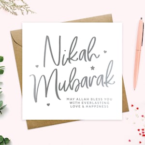 May include: A white card with silver lettering that says "Nikah Mubarak" and "May Allah bless you with everlasting love & happiness".