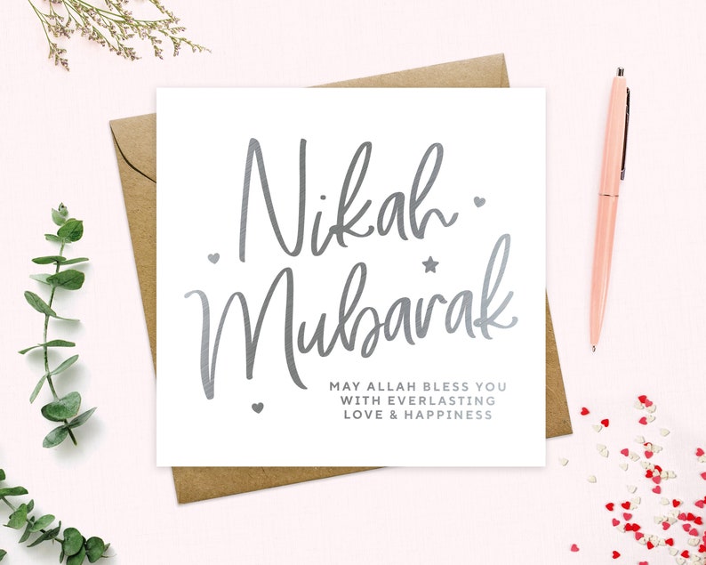 May include: A white card with silver lettering that says "Nikah Mubarak" and "May Allah bless you with everlasting love & happiness".
